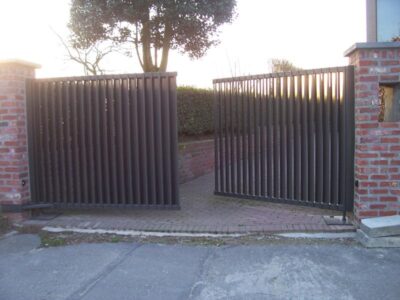 Dubbel opendraaiende metalen poort met lamellen uitvoering en ondergrondse automatisatie. 14. Metalen poort