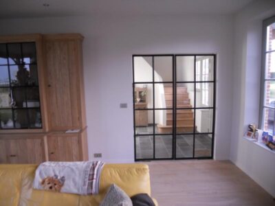 Dubbel opendraaiende metalen binnendeur met vloerpompen en mastiek look afwerking. 8. Metalen binnendeur