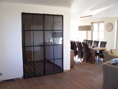 Dubbel opendraaiende stalen binnendeur met enkel glas en mastiek look afwerking. 9. Stalen binnendeur